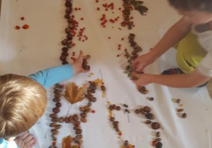 Dzieci tworzą ludzika z darów jesieni.